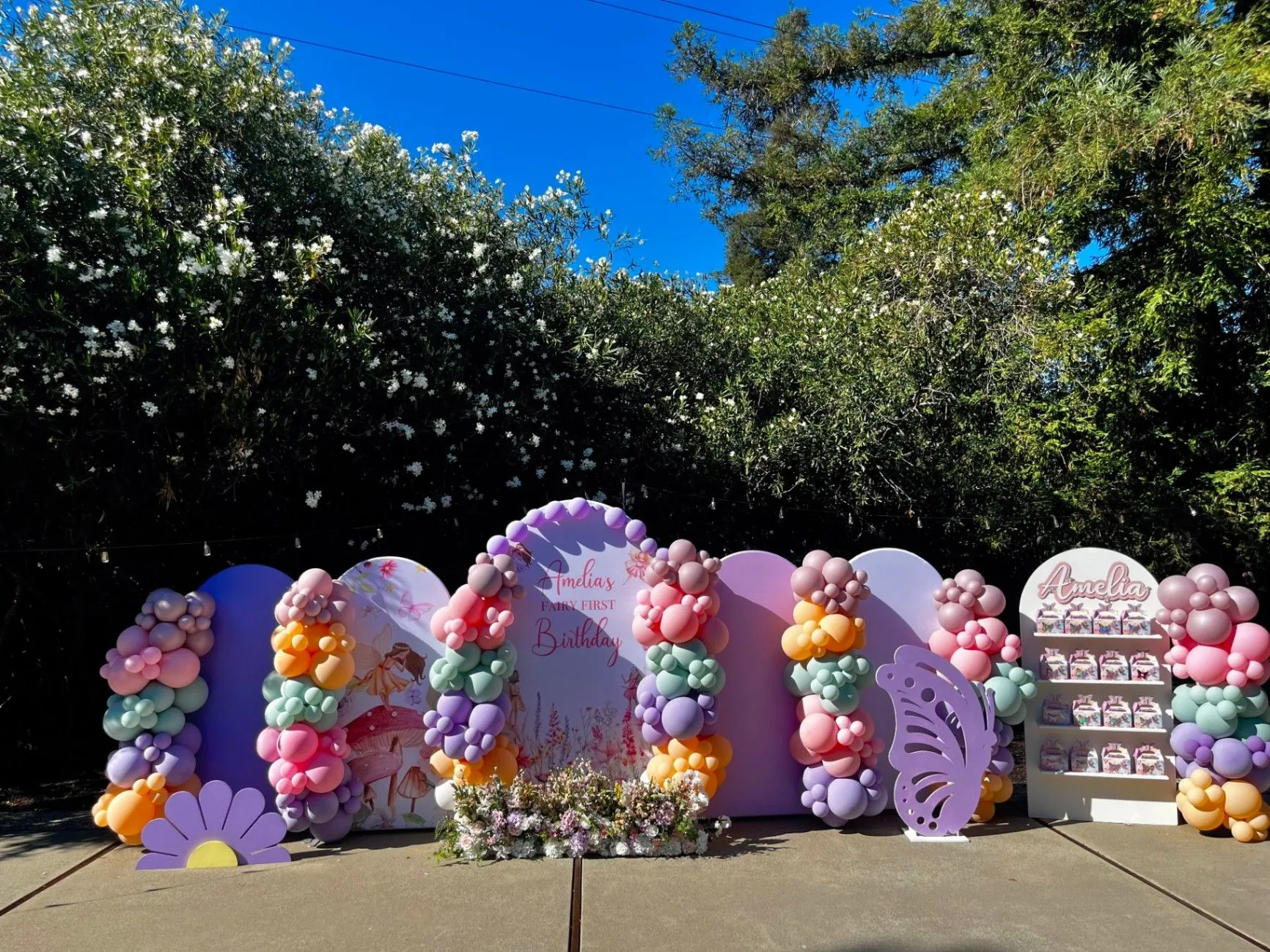 Outdoor fairy-themed birthday setup with pastel balloons and custom backdrops