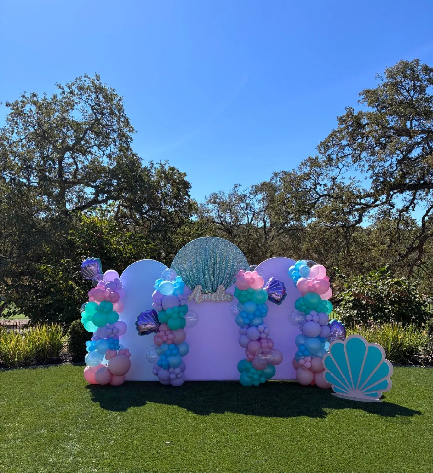 Outdoor mermaid-themed backdrop with pastel balloons and shell details